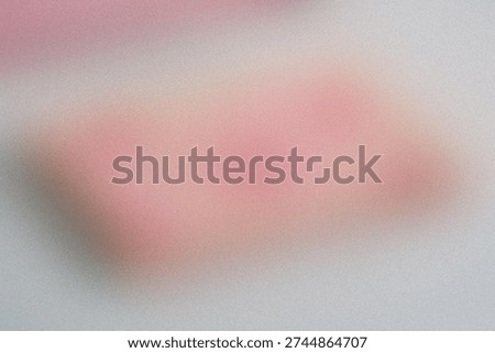 Blurred view of a pinkish rectangular object against a textured background