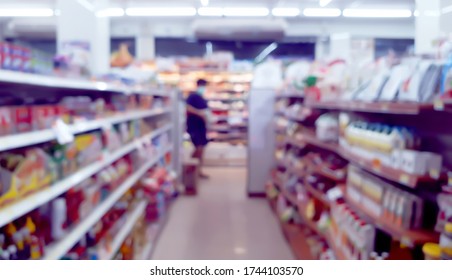 Blurred View Of Products On Display Shelf At Convenience Store. A Man Wearing Surgical Mask To Protect Coronavirus At Public Space.