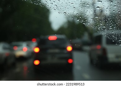Blurred view of road through wet car window. Rainy weather - Shutterstock ID 2231989513
