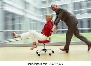 Blurred View Of Two Businesspeople Playing With A Computer Chair In Office Setting