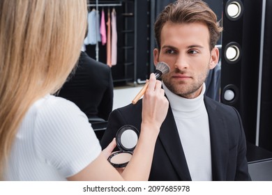 Blurred Visage Artist Applying Face Powder With Cosmetic Brush On Man In Photo Studio