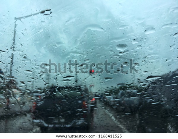 Blurred\
water drop on the car glass background, blurred of outside road and\
traffic view through car window during\
raindrop.