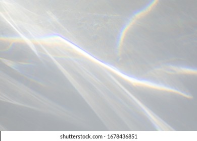 Blurred water texture overlay effect for photo and mockups. Organic drop diagonal shadow caustic effect with rainbow refraction of light on a white wall.