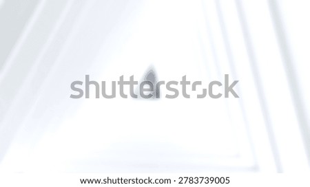 A blurred white triangular tunnel creates a soft abstract background with light gradients and a central focal point in a minimalist architectural style.