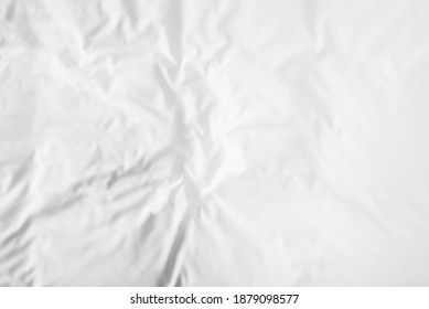 Blurred White Wrinkled Bedsheet Or Fabic Texture Rippled Surface Background. Unmade Of Bedsheet In The Morning. Top View And Soft Focus With Copy Space Background.