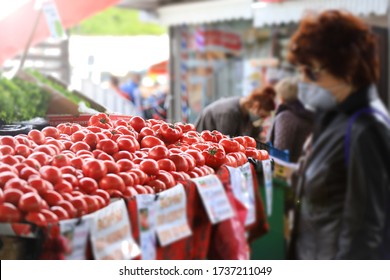 Blurred Woman With Face Mask Look At Red Organic Tomatoes On A Farmer Market. 