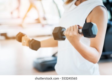 Blurred Woman Lifting Dumbbells in Weight Training Fitness - Sport and Lifestyle Concept - Shutterstock ID 553245565