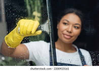 Blurred Woman In Rubber Glove Cleaning Glass With Window Wiper