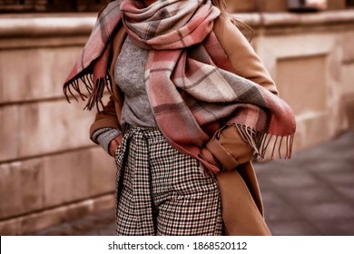 Blurred young woman with cropped head in cozy scarf and brown coat walking on the street. Outdoor portrait in daylight. Warm winter clothes concept - Powered by Shutterstock