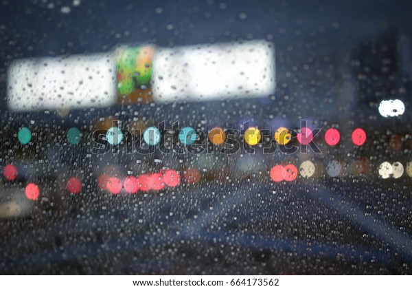 Blurred,out of\
focus colorful bokeh cars light on the city road,highway background\
in the rain storm rush hour,traffic jam evening night with rain\
water drops on the\
windshield