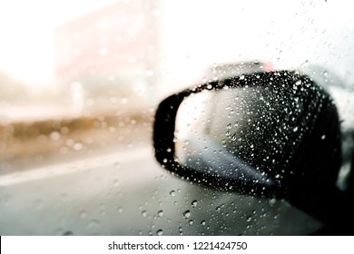 Blurred,Rain drops on a car window with the mirror in the background