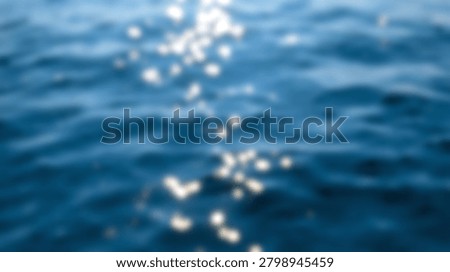 A blurry abstract background of deep blue ocean water with bright sparkling sunlight reflections creating a beautiful bokeh effect