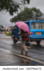 Blurry Abstract Photo Of Street Photography, People Using Umbrella In Urban Area During Rainy Season.