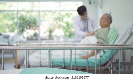 Blurry Background Of Asian Doctor Check Up Body Or Heart By Stethoscope Of Sick Old Senior Elderly Patient On Bed In Hospital In Medical And Healthcare Treatment At Nursing Home. People Lifestyle