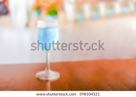 Blurry background of blue cocktail in glass on wooden table.