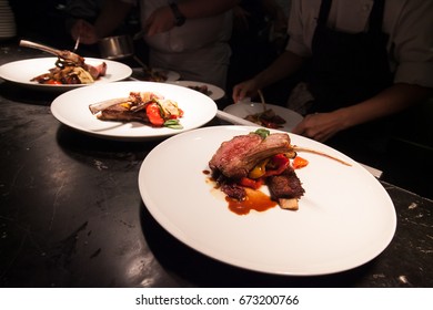 Blurry Background Of Chef In Hotel Or Restaurant Kitchen Cooking With Lamb And Decoration For Luxury Dinner Party.