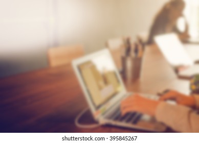 Blurry background girl using laptop in office.