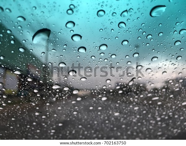 Blurry background, raindrops on the windshield,\
windshield view on a rainy\
day.