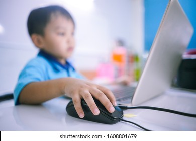 Blurry Background Of Small Child Staring At Computer Screen, Close Up Image Of Kid Hand Clicking Computer Mouse On White Desk With Blurry Face In Background