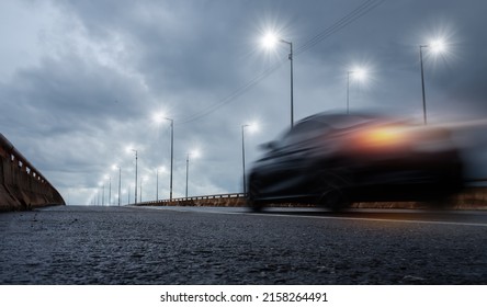 Blurry of car driving fast on bridge during hard rain with storm clouds as background,selective focus and long shutter speed exposure.Concept of rainy season,transportation and travel.