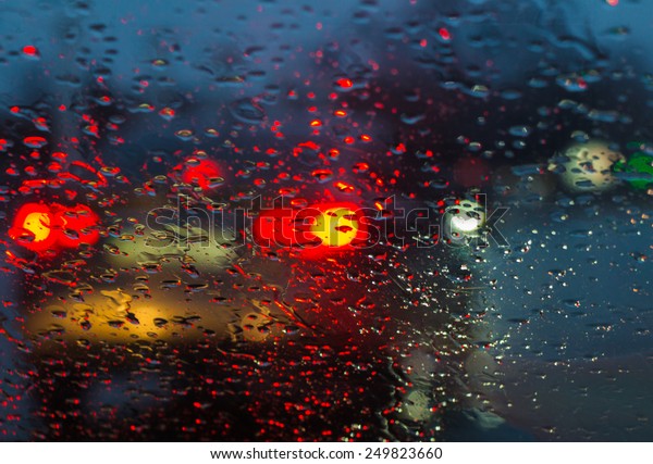 Blurry car silhouette seen through raindrops\
on the car windshield