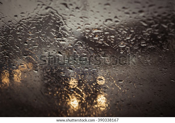 Blurry cars silhouette seen through water\
drops on the car\
windshield