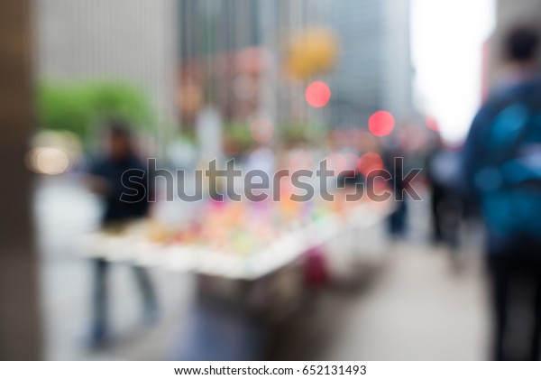 Blurry city street scene. Daytime shot of a table\
full of colorful toys, on sale by a street vendor in New York City,\
near Times Square.