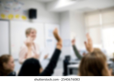 Blurry classroom scene with students raising hands. Teacher in background. Engaged students, active learning, classroom interaction, educational setting. High school education in blurry background. - Powered by Shutterstock