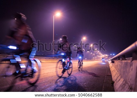 Blurry of Cyclists ride through lighted city