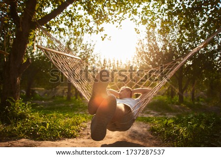 blurry and defocus relaxing in hammock in sunny day. man rest in garden. summer vibes in forest