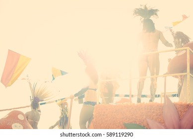 Blurry defocused silhouette of unrecognizable joyful dancing woman wearing carnival feathers costume on sunny street outdoors background. Back view photography