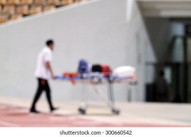 Blurry Doctor Stand By With Stretcher And Hospital Trolley For Help At Football Stadium