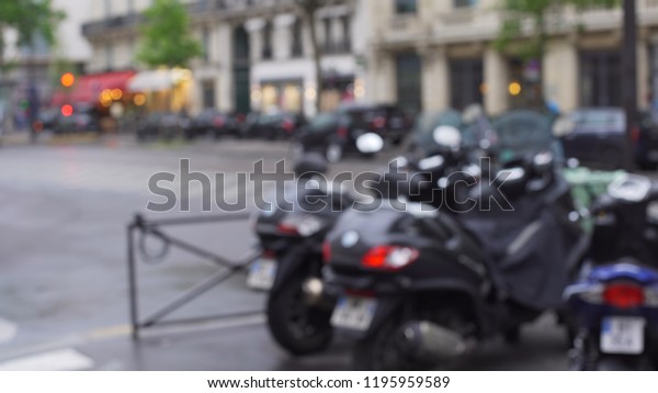 Blurry exterior background of motorbikes parked in\
the street in Paris,\
France