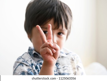 Blurry Face Of Boy Looking Through His Fingers At Camera,Selective Focus Of Kid Primary School Counting Number Second,Cute Kid Showing Numbers Two With Fingers,Education Or Toddler Development Concept