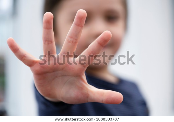 Blurry face of little boy showing five fingers at camera,Selective focus of kid primary school counting number five,Cute kid showing five numbers with fingers, Education or Toddler development concept