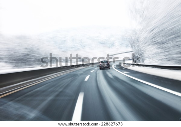 Blurry fast turn at the icy snow road with one\
car in the foreground. Motion blur visualizies danger of the high\
speed and dynamics.