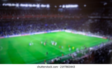 Blurry Football Stadium Full Of Spectators. Soccer Arena With Blur On Game Day. Crowd Watching Football Game At The Stadium. Football Arena Blurred Background.