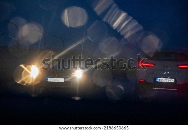 blurry glare from\
headlights on in bad rainy weather at night on a turn when two cars\
collide horizontal\
