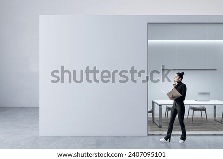Blurry happy young female walking in modern light concrete and glass office box interior with mock up place on walls and wooden floors. Designer concept