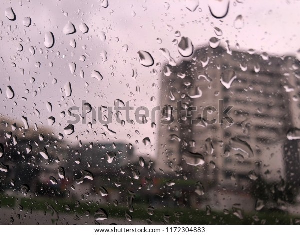a blurry with heavy rain. A\
rain storm, raindrops splatter on the windshield  and car\
window
