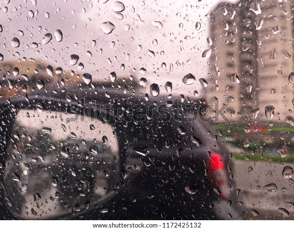 a blurry with heavy rain. A\
rain storm, raindrops splatter on the windshield  and car\
window