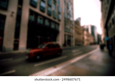 A blurry image of an alleyway in a city with a red car parked in the distance. The street is empty and there are buildings on either side. The image has a bokeh effect. - Powered by Shutterstock