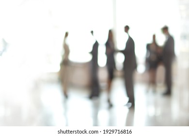 Blurry Image Of A Group Of Business People Standing In The Office Lobby.