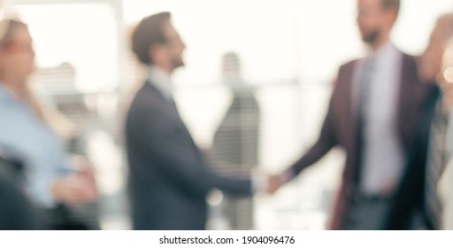 Blurry Image Of A Handshake Of Business People At A Meeting In The Office.