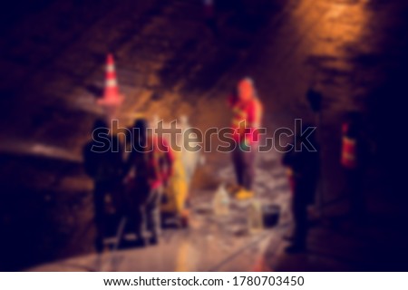 Blurry image of machine with construction worker is working at night in construction site with spotlight and black background. The concept of hard work and over time.