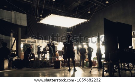 Blurry image of making movie video in big production studio and film crew team shooting or recording by professional digital camera and lighting set equipment.