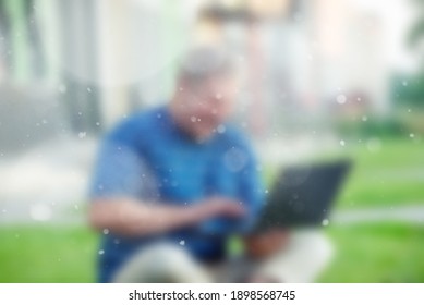 Blurry Image - Male Viewing Online Content On A Laptop And Laughing While Sitting On The Lawn In The City