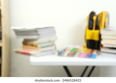 Blurry image of a study table with stacked books, colorful markers, and a yellow backpack. Ideal for illustrating concepts of education, study space organization, back-to-school themes - Powered by Shutterstock - Get 15% off with code: PIKWIZARD15