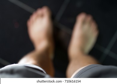 The Blurry Image Of The Viewer's Eyes Looking Down At His Own Bare Feet On The Black Tile Floor.