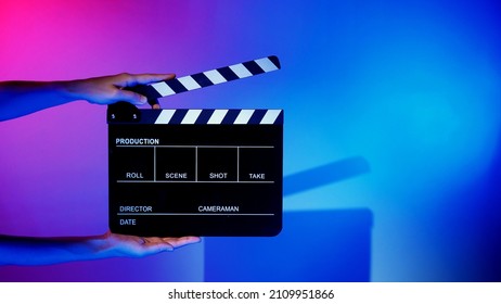 Blurry Images Of Movie Slate Or Clapper Board. Hand Holds Empty Film Making Clapperboard On Color Background In Studio For Film Movie Shooting Or Recording. Film Slate For Youtuber Video Production.